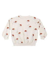 A cream-colored crewneck sweatshirt featuring an all-over print of Santa Claus faces and small sleighs, displayed flat against a solid white background.