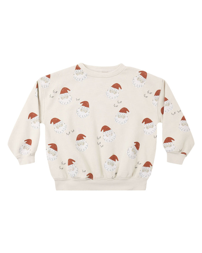 A cream-colored crewneck sweatshirt featuring an all-over print of Santa Claus faces and small sleighs, displayed flat against a solid white background.