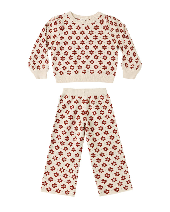 A two-piece knit loungewear set for kids, featuring a cropped long-sleeve top and matching pants in cream with a repeating red floral pattern, displayed on a solid white background.