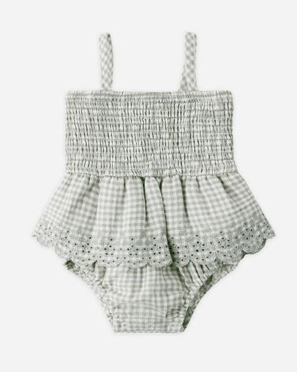 Checkered baby romper with lace details on a white background