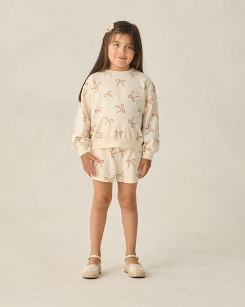 Young girl wearing a patterned outfit on a plain background