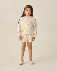 Young girl wearing a patterned outfit on a plain background