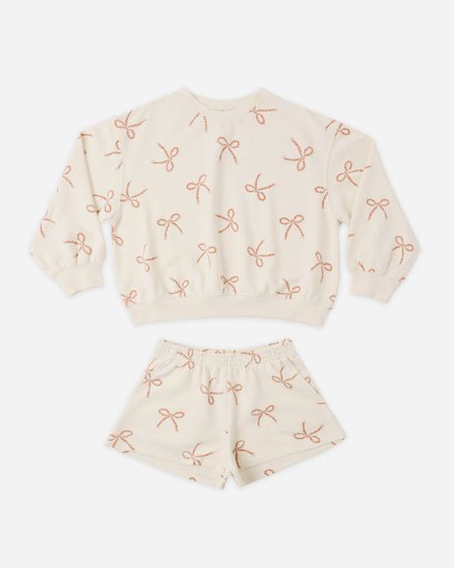 Children's outfit with top and shorts featuring bow pattern on a white background