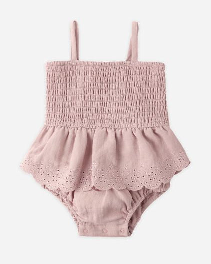 Pink baby romper with smocked top and ruffled bottom on a white background