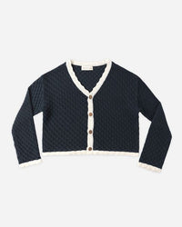 Navy blue cardigan with white trim and brown buttons on a light gray background