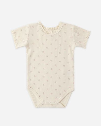 Beige baby onesie with small patterns on a white background