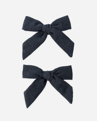 Two dark blue hair bows on a white background
