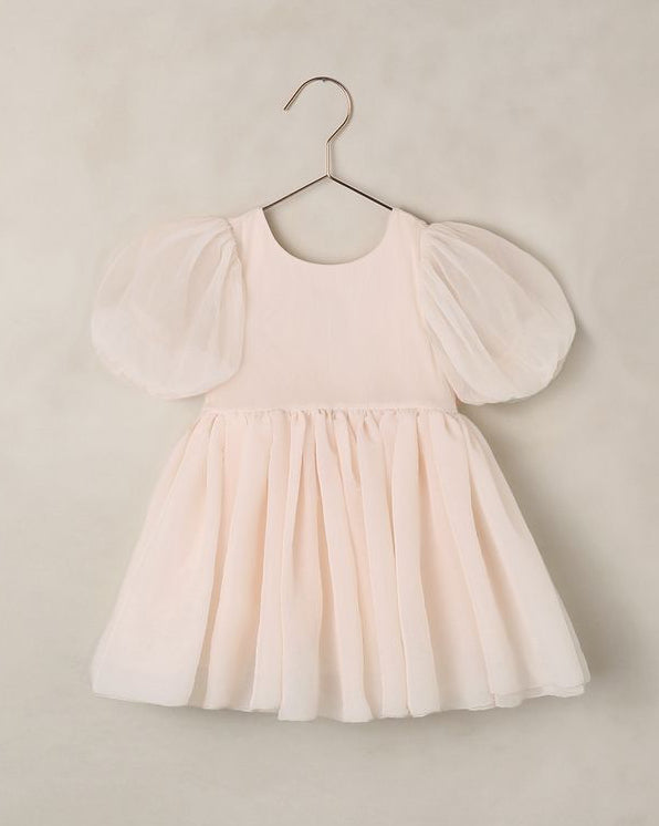 Blush pink dress with puff sleeves on a hanger against a beige background