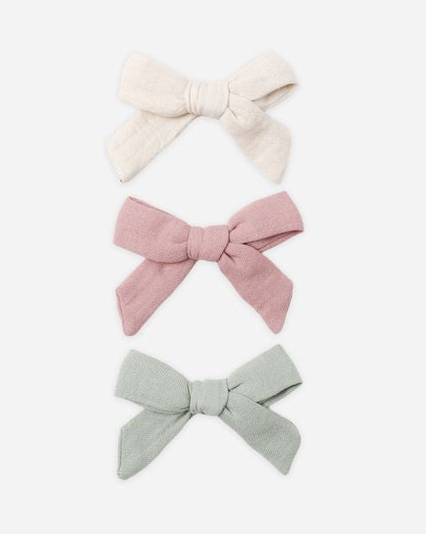 Three hair bows in cream, pink, and gray on a white background