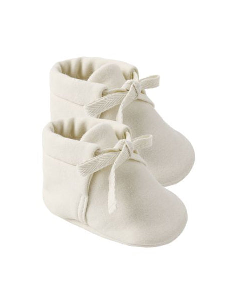 Pair of white baby shoes with bows on a white background