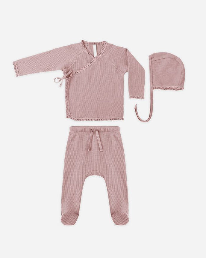 Pink baby outfit with top, pants, and hat on a white background