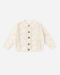 Cream-colored knitted cardigan on a light beige background