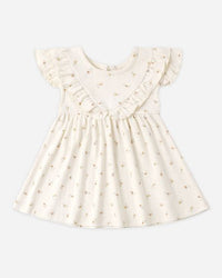 White dress with ruffled details on a light beige background