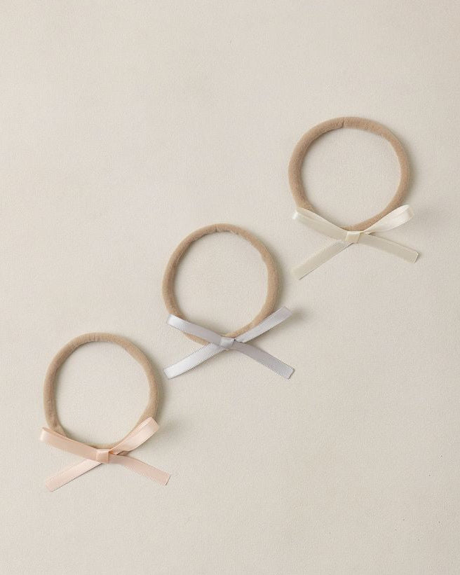 Three headbands with ribbons on a beige background